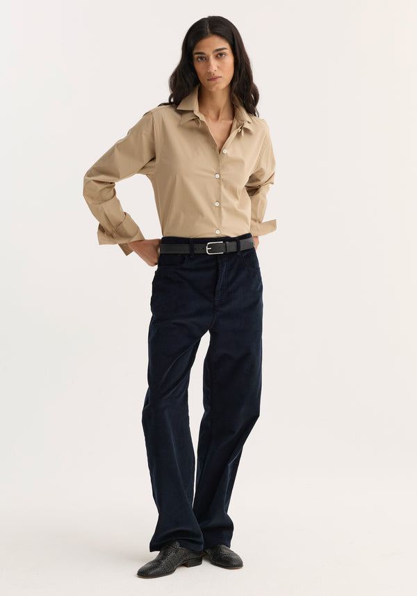 Woman wearing Double collar shirt | wheat, tucked into navy corduroy trousers, with black belt and shoes. Shirt features detachable collar, relaxed fit.