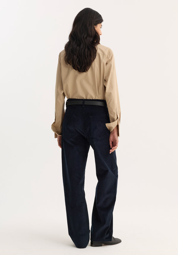Woman wearing a Double collar shirt | wheat, buttoned and tucked into navy trousers, with wavy hair down her back, showcasing the shirt's relaxed fit.