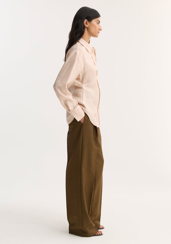 Woman wearing Silk Shaped Shirt | Rose, a relaxed, button-down silk blouse with a rounded hem, paired with high-waisted, wide-leg trousers for a minimalist look.