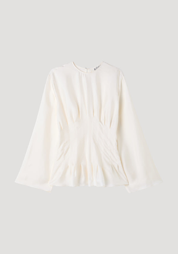 Pleated silk top in cream showcases elegant pleats, long flared sleeves, and a peplum hem with a back keyhole closure, crafted from 100% silk.
