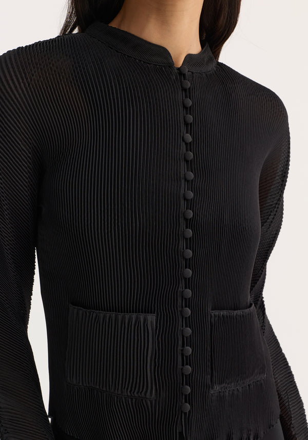 Plissé cardigan in black with pleats, stand-up collar, fabric-covered buttons, and patch pockets. Slightly cropped fit, worn by model; elegant for special occasions.