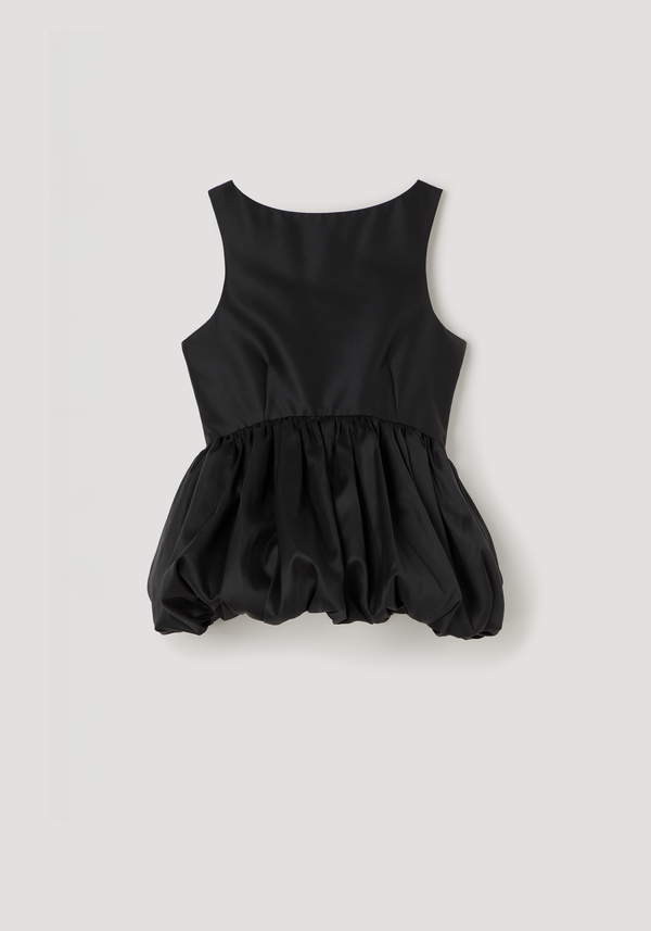 Voluminous boat-neck top in black with a sleeveless design, low back, and architectural peplum skirt, laid flat showcasing its elegant silhouette against a light backdrop.