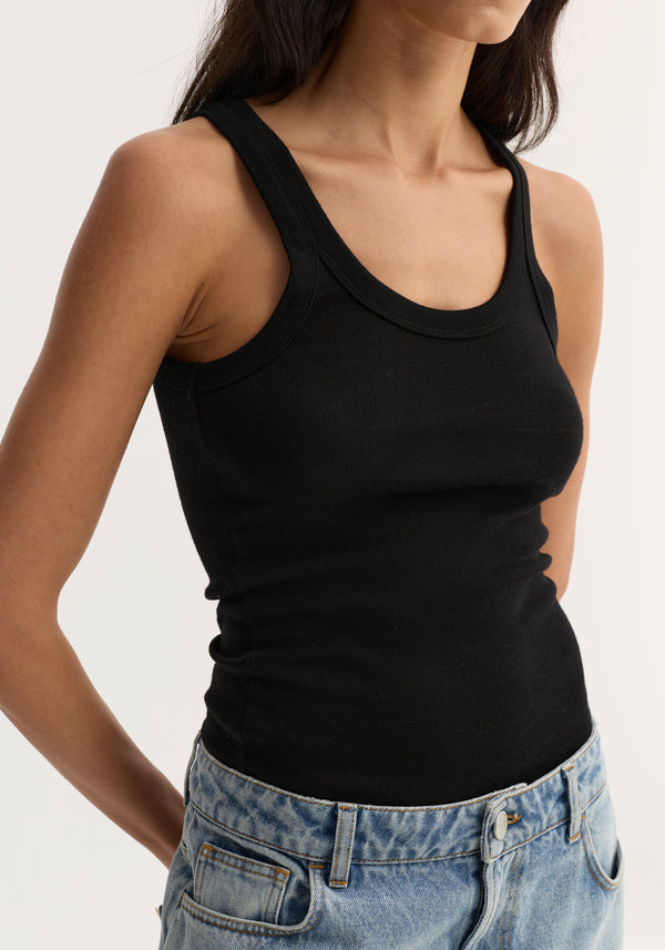 Merino scoop neck top | black shown in a close-up, fitted ribbed design, tucked into light-wash jeans. Made from 100% merino wool for versatile layering.