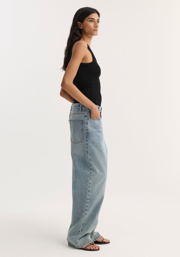 Merino scoop neck top | black, shown in side profile, tucked into loose light-wash jeans. Model, 178cm, wears size 36 with black strappy sandals.