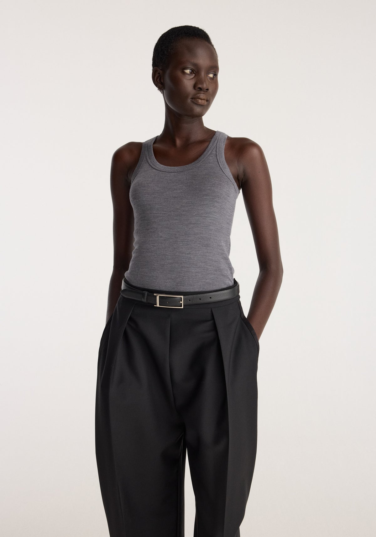 Merino scoop neck top | mid grey melange worn by a model with black trousers in a studio setting