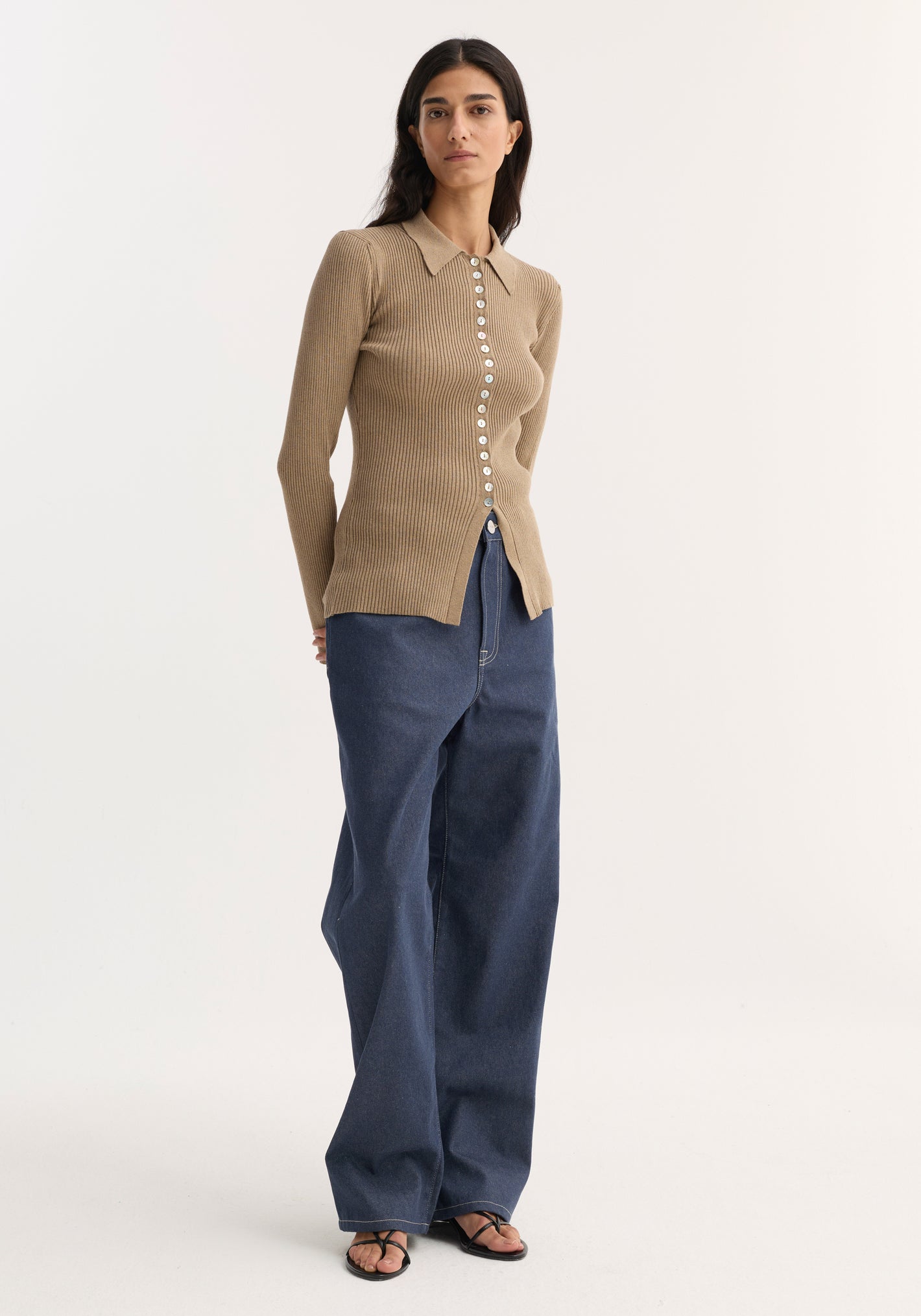 Elongated rib cardigan in taupe melange with a fitted silhouette, pointed collar, and white buttons, paired with wide-leg jeans and black sandals.
