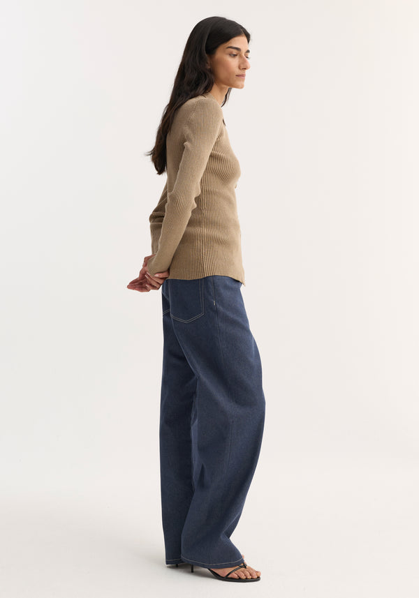 Woman in profile wearing Elongated rib cardigan | taupe melange, fitted with button closures, collar, paired with dark-blue jeans and black strappy sandals.