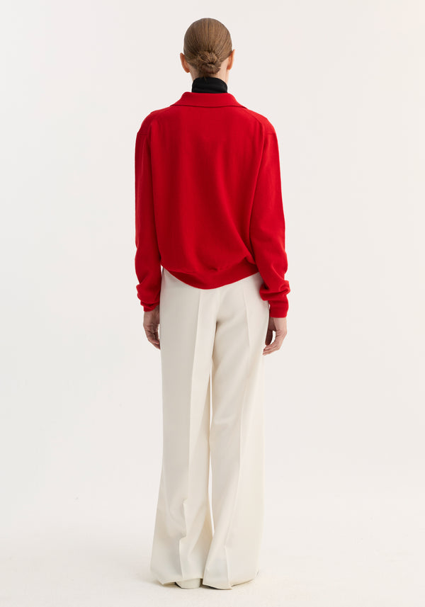 Back view of person in a Wool cashmere polo | red, featuring a structured collar and three-button front, paired with wide-leg white trousers.