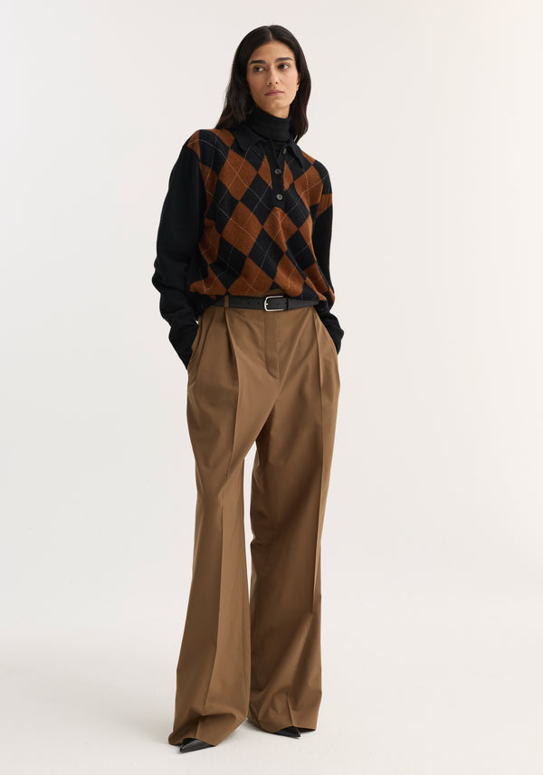Model wearing Mid-waist tailored trousers in mocha with a structured waistband, double pleats, and wide legs, styled with a black and brown sweater.