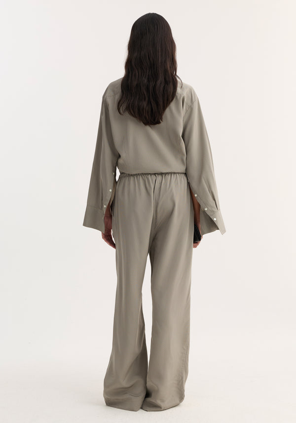 Back view of Relaxed fit trousers in light grey stripe, featuring wide legs and a drawstring waistband, worn with a matching pinstripe shirt.