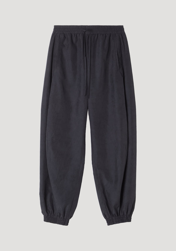 Balloon track pants in a crinkled texture with elastic waistband and cuffs, featuring a drawstring and slanted welt pockets for a voluminous silhouette.