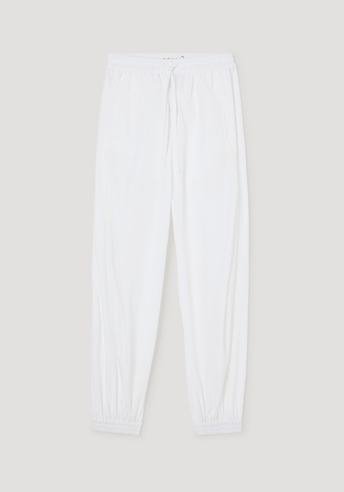 Balloon track pants in optic white, featuring a crinkled texture, elastic waistband with drawstring, side pockets, and elastic cuffs for a voluminous leg style.