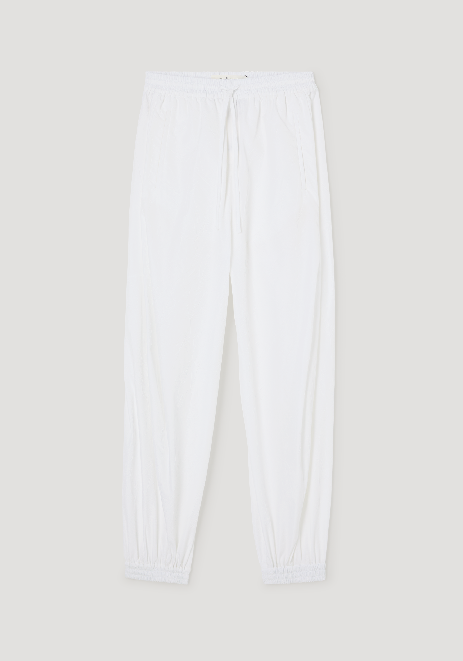 Balloon track pants in optic white, featuring a crinkled texture, elastic waistband with drawstring, side pockets, and elastic cuffs for a voluminous leg style.