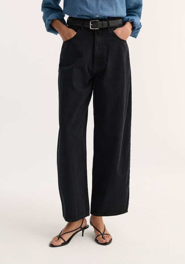 Barrel leg denim | black featuring high-waisted, loose-fitting black wide-leg trousers, styled with a blue chambray shirt, black leather belt, and strappy kitten-heel sandals.