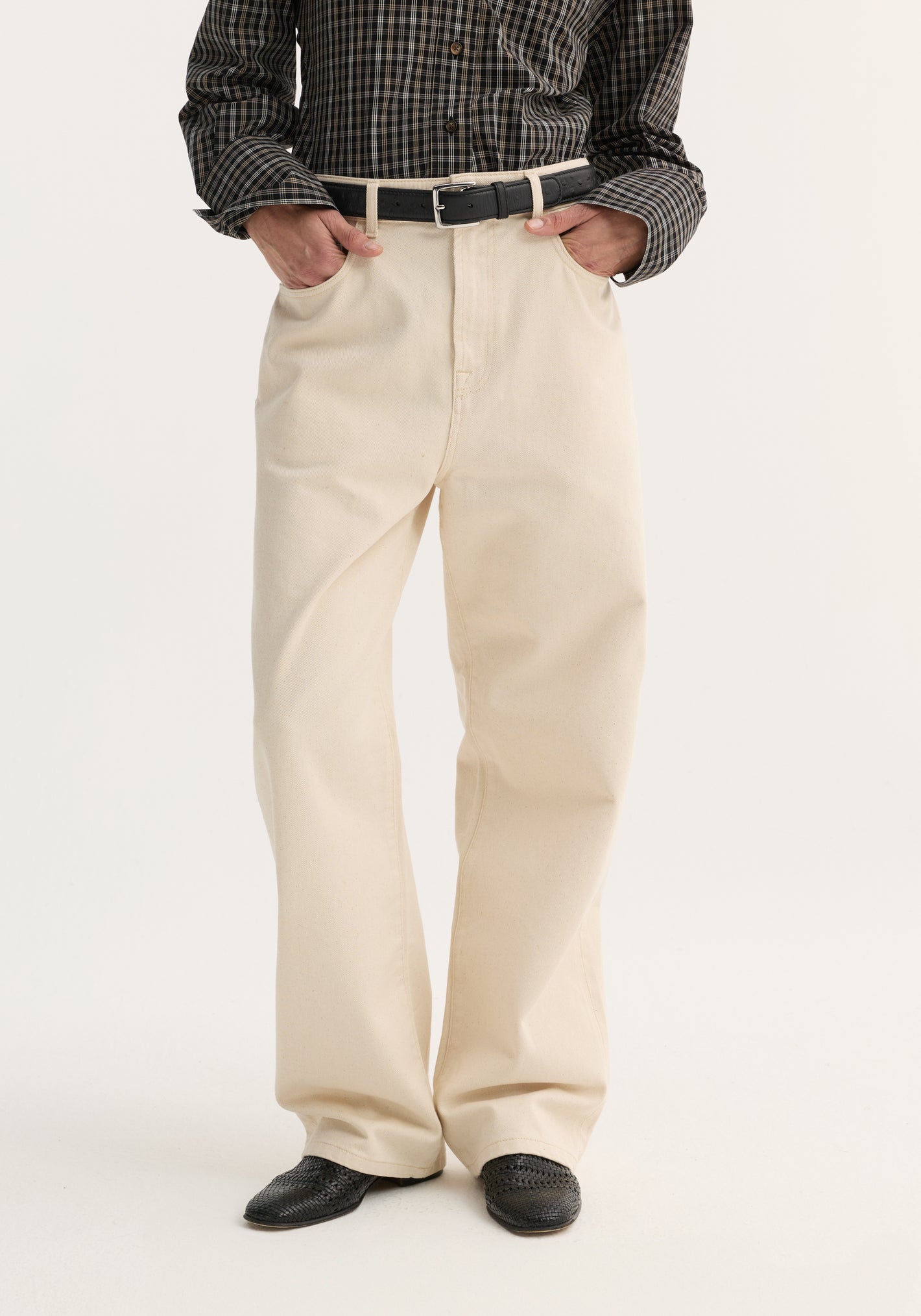 Baggy fit denim | ecru: Cream wide-leg trousers with a high waist, styled with a black leather belt and woven-leather slip-on shoes, showcasing relaxed, everyday wear.