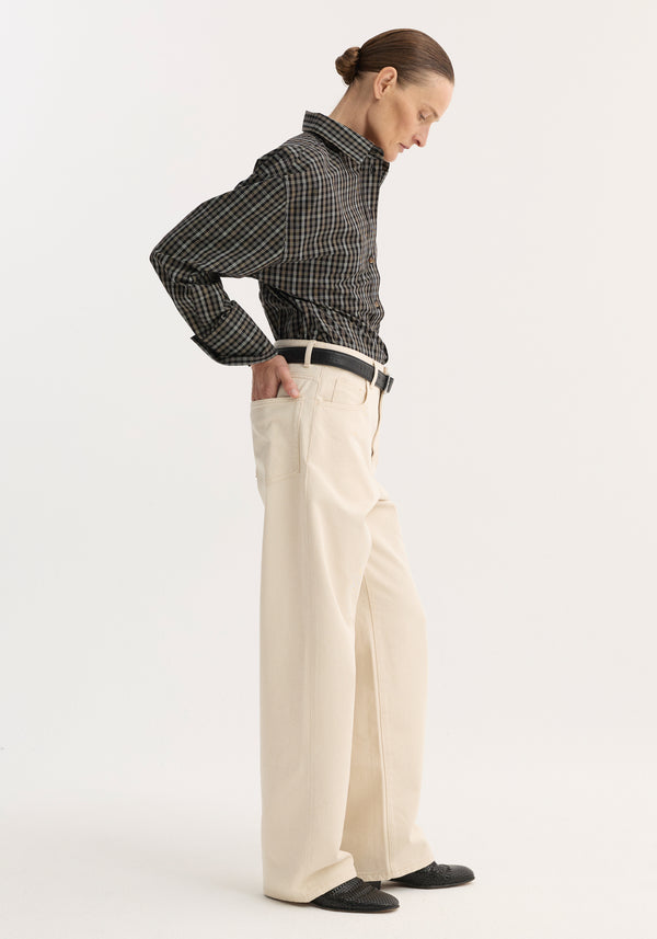 Side profile of a person wearing baggy fit denim in ecru, paired with a dark plaid shirt, showcasing a casual, oversized style.