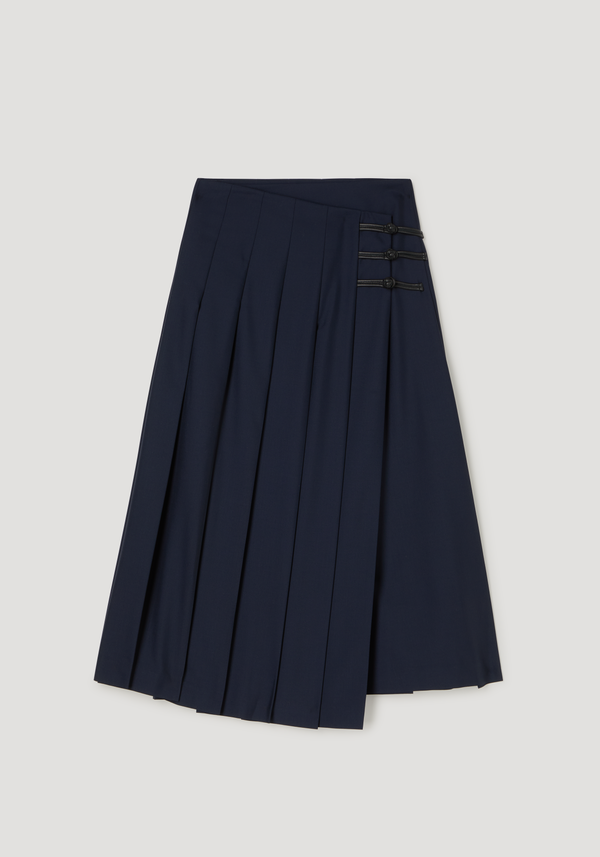 Pleated wool skirt with leather closures, featuring a fitted hip and voluminous pleats, secured by black cord-and-knot closures.