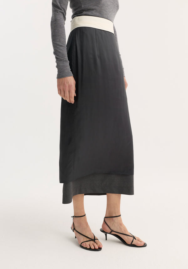 Inside-out skirt in dark grey melange with contrasting off-white waistband, two-layer design, and black heeled sandals, highlighting reversed construction with visible lining.