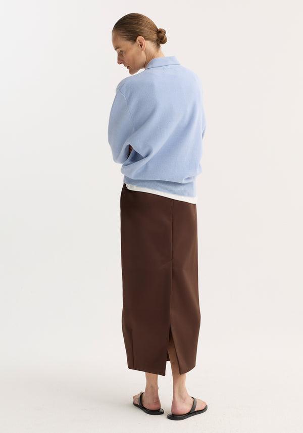 Person wearing Balloon column skirt | espresso, featuring a high waist, sculptural balloon cut, and rear slit, paired with a pale-blue knit top and black sandals.