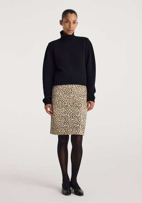 Woman wearing a black turtleneck sweater paired with a beige Pony hair pencil skirt | cheetah featuring a spotted cheetah pattern, black tights, and black shoes.