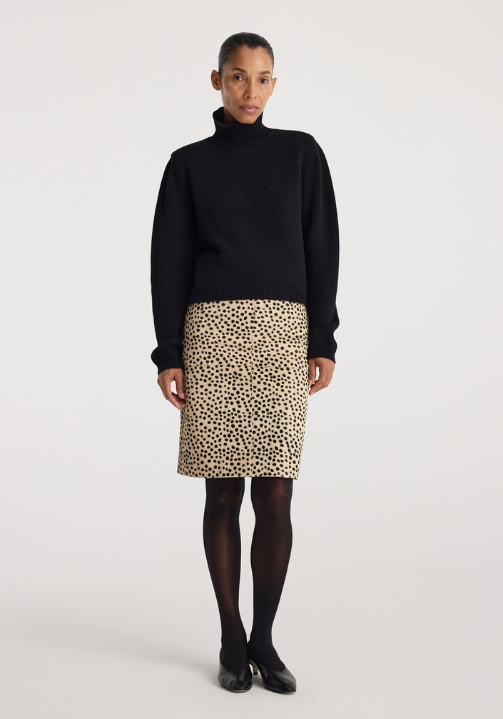 Woman wearing a black turtleneck sweater paired with a beige Pony hair pencil skirt | cheetah featuring a spotted cheetah pattern, black tights, and black shoes.