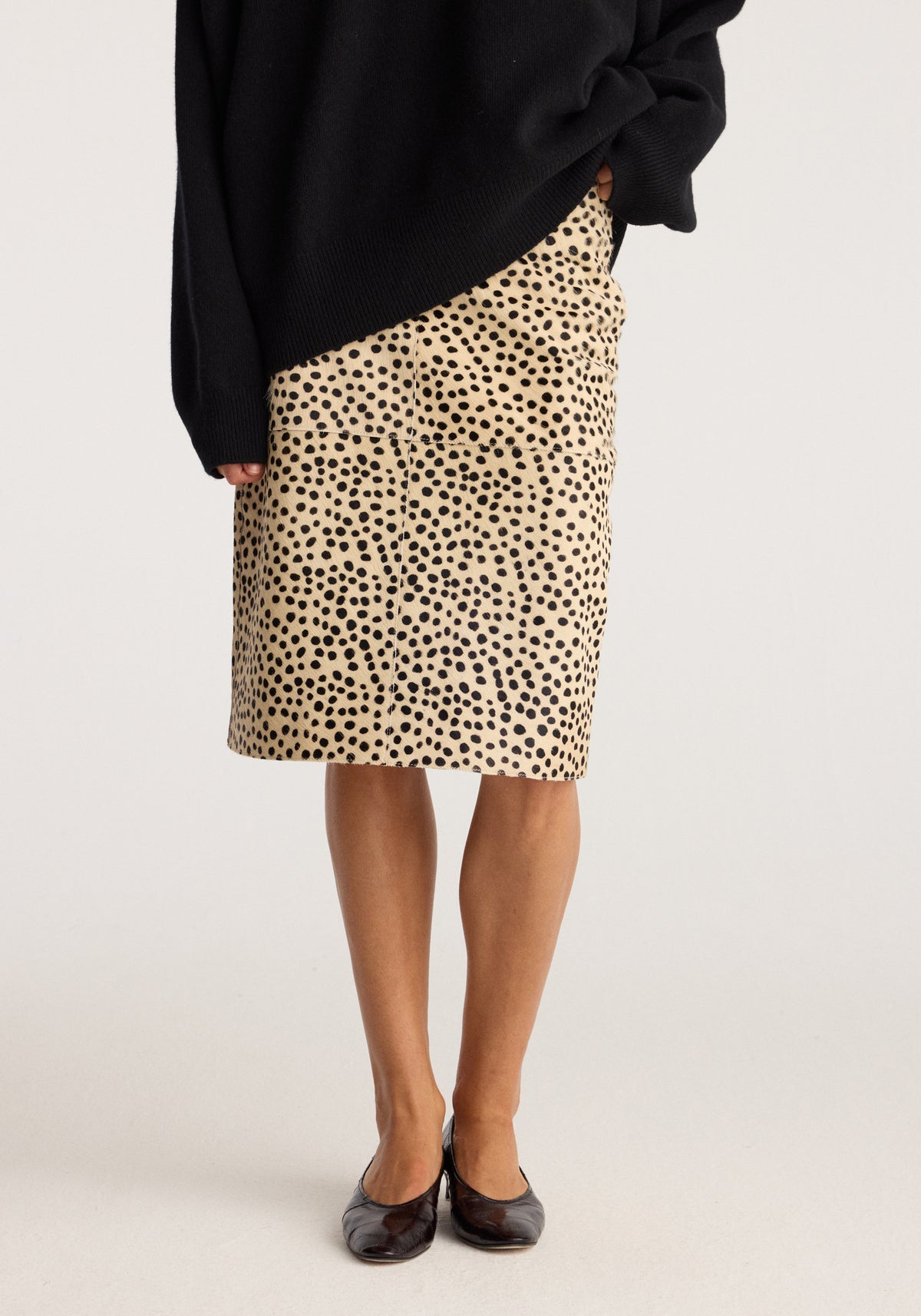 Pony hair pencil skirt | cheetah with a beige and black spotted pattern styled with a black sweater and black flats in a fitted knee length silhouette