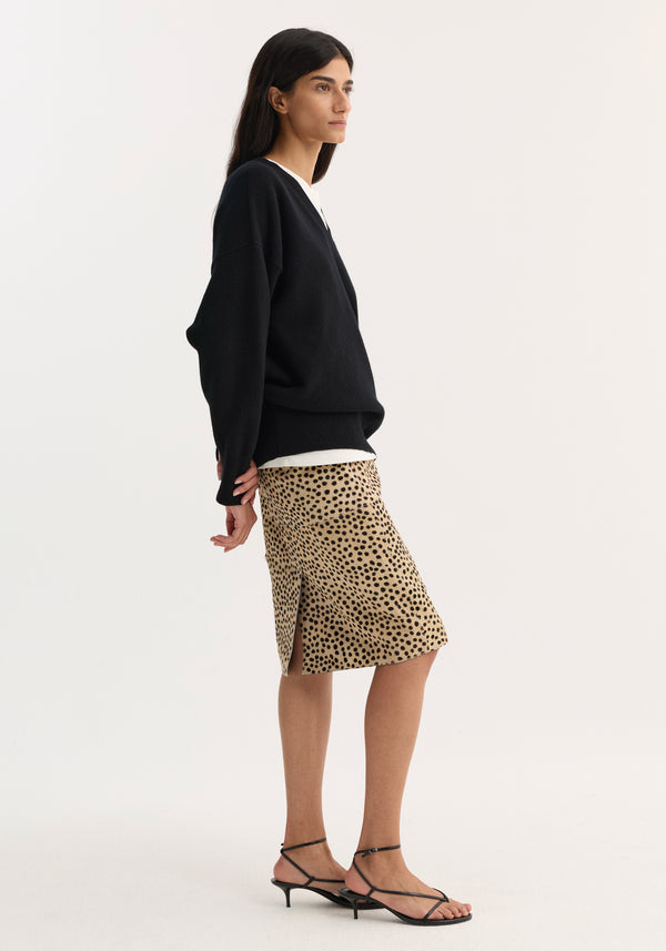 Model in a black sweater and sandals wears a pony hair pencil skirt in cheetah print, featuring a sleek fit and back slit.
