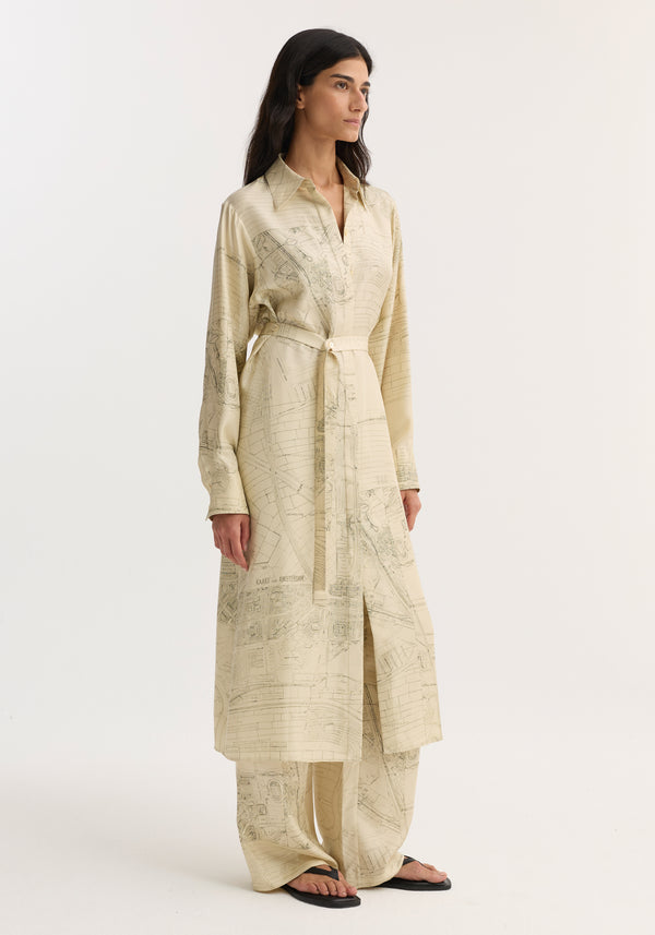Woman wearing Silk open back wrap dress | Amsterdam, featuring map print, classic collar, long sleeves, cinched waist, with matching wide-leg trousers and black sandals.