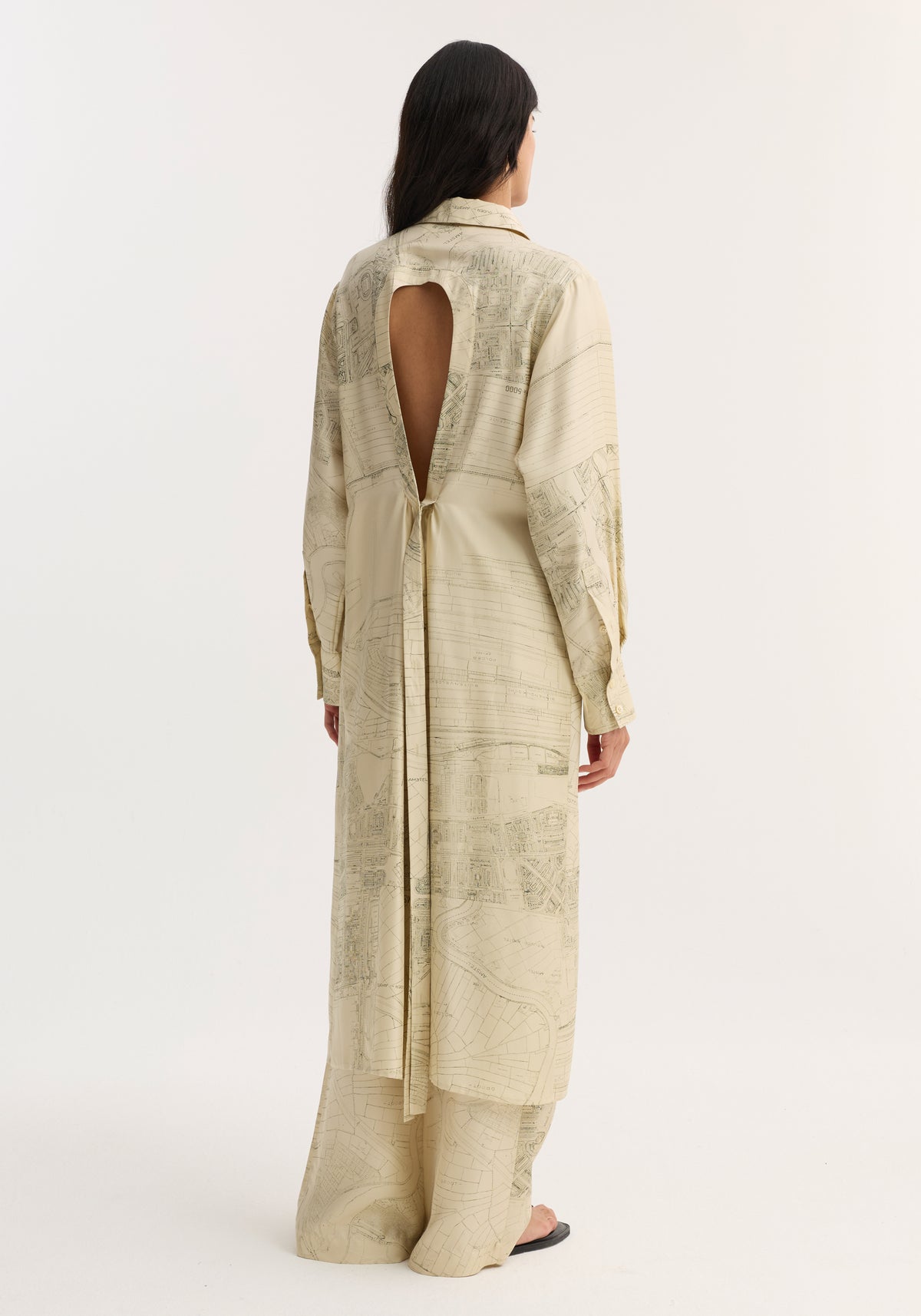 Person wearing a Silk open back wrap dress | Amsterdam with a keyhole back, tie waist, and matching wide-leg pants, showcasing a map motif.