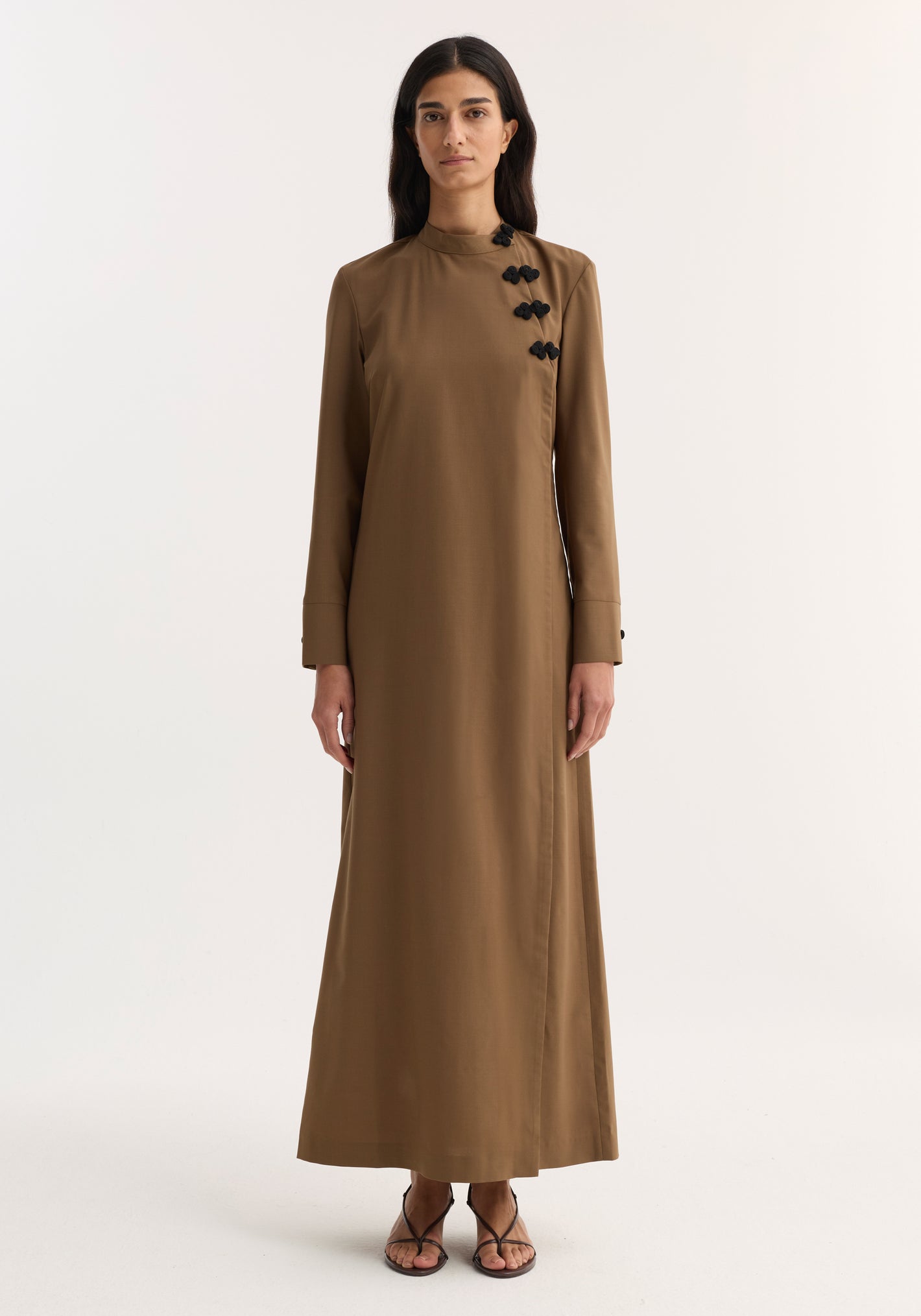Mandarin Dress | mocha: Woman in full-length, long-sleeved brown dress with asymmetrical pankou closures and side split, paired with black strappy sandals.