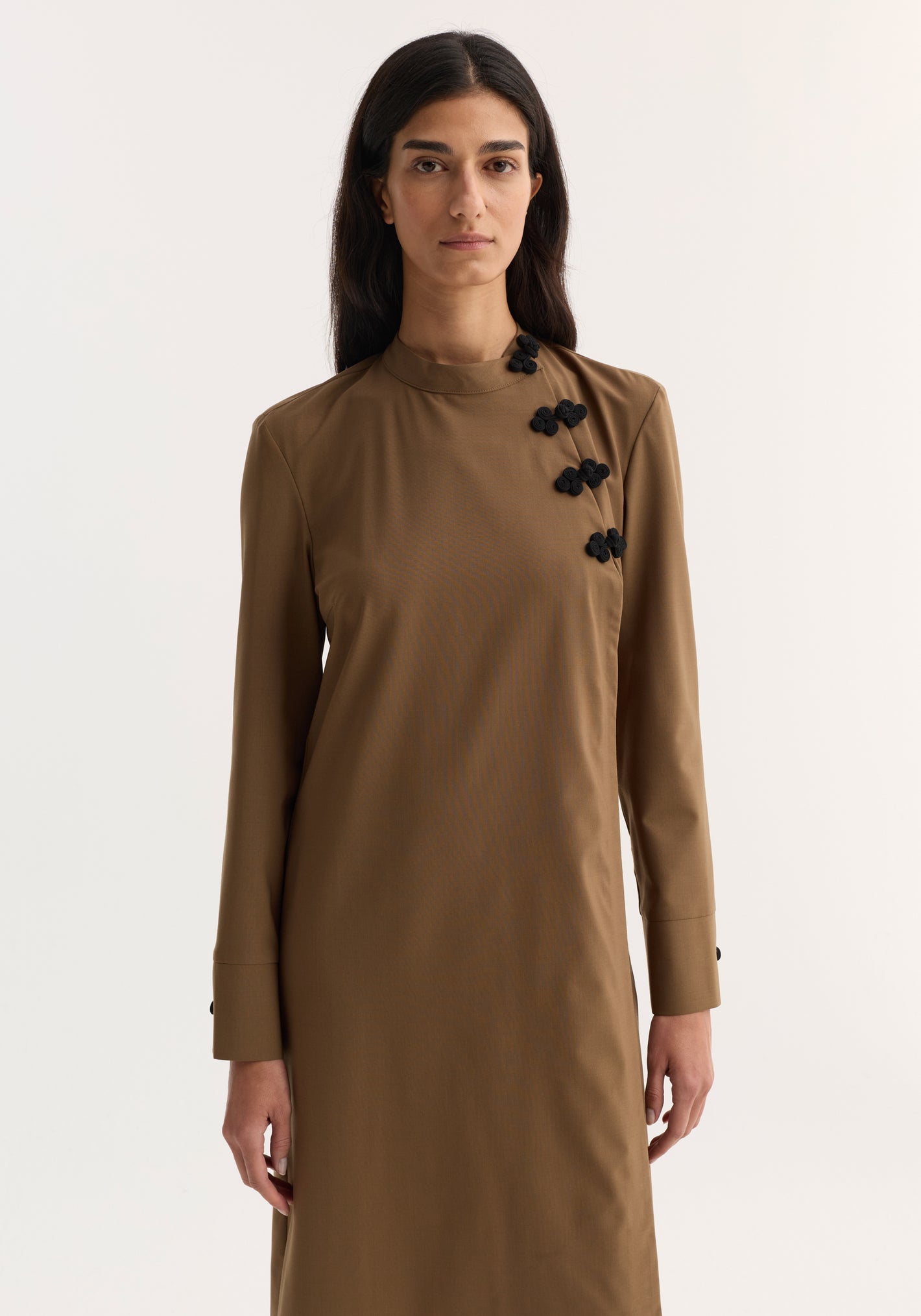 Mandarin Dress in mocha with long sleeves, asymmetrical pankou closures, and side split, modeled by a woman against a light background, showcasing elegant minimalism.