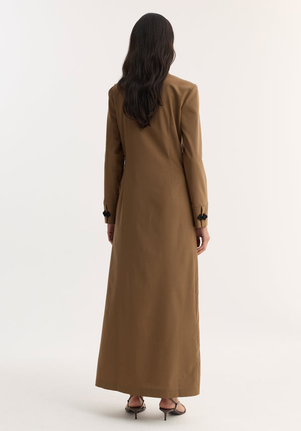 Mandarin Dress | mocha: Back view of a woman in a camel-brown, floor-length coat-style dress with black pankou closures, long sleeves, and high-heeled sandals.