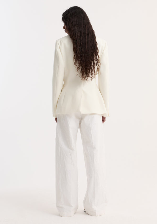 Back view of a model in an Hourglass shaped blazer | off white, showcasing a cinched waist, sharp notch lapel, and single button closure.