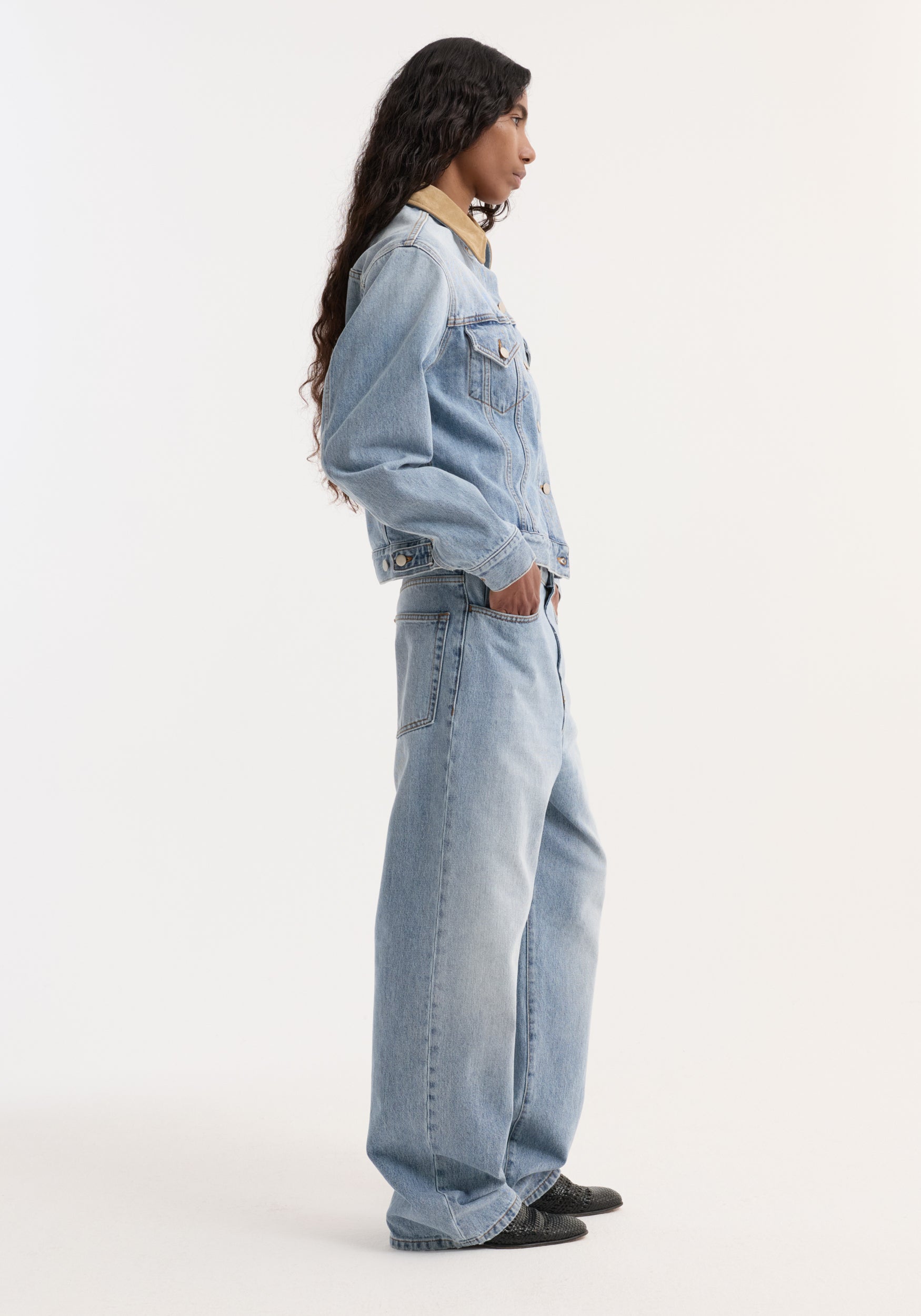 Model wearing the Suede collar fitted denim jacket | classic blue, featuring a contrasting tan suede collar, chest pockets, and matching loose-fit denim jeans.