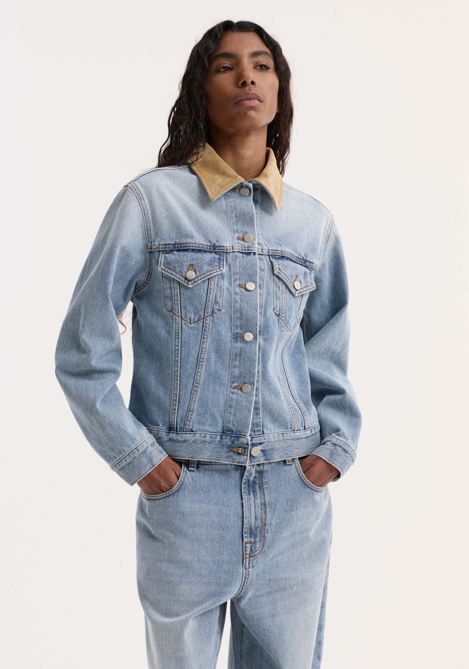 Suede collar fitted denim jacket | classic blue shown on a model wearing a light-wash outfit with flap chest pockets and hands in jeans' pockets.