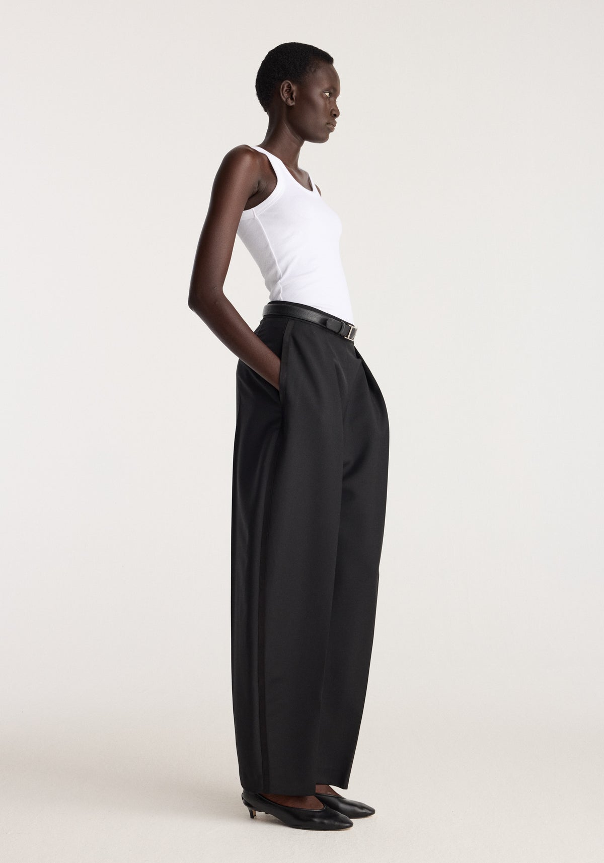 Scoop knitted top | optic white worn by a model with black wide leg trousers in side profile against a neutral studio background