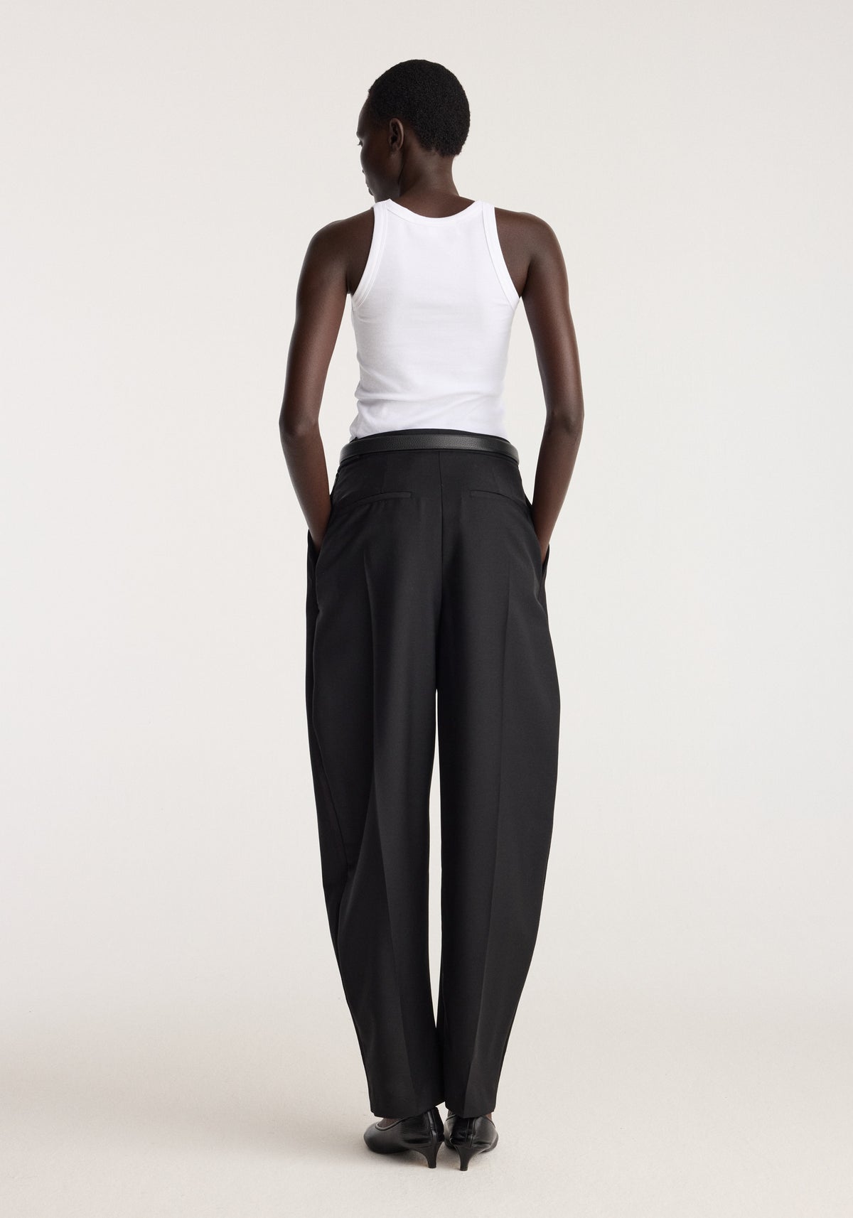 Scoop knitted top | optic white shown from the back on a model, featuring a fitted sleeveless silhouette styled with black trousers and black shoes