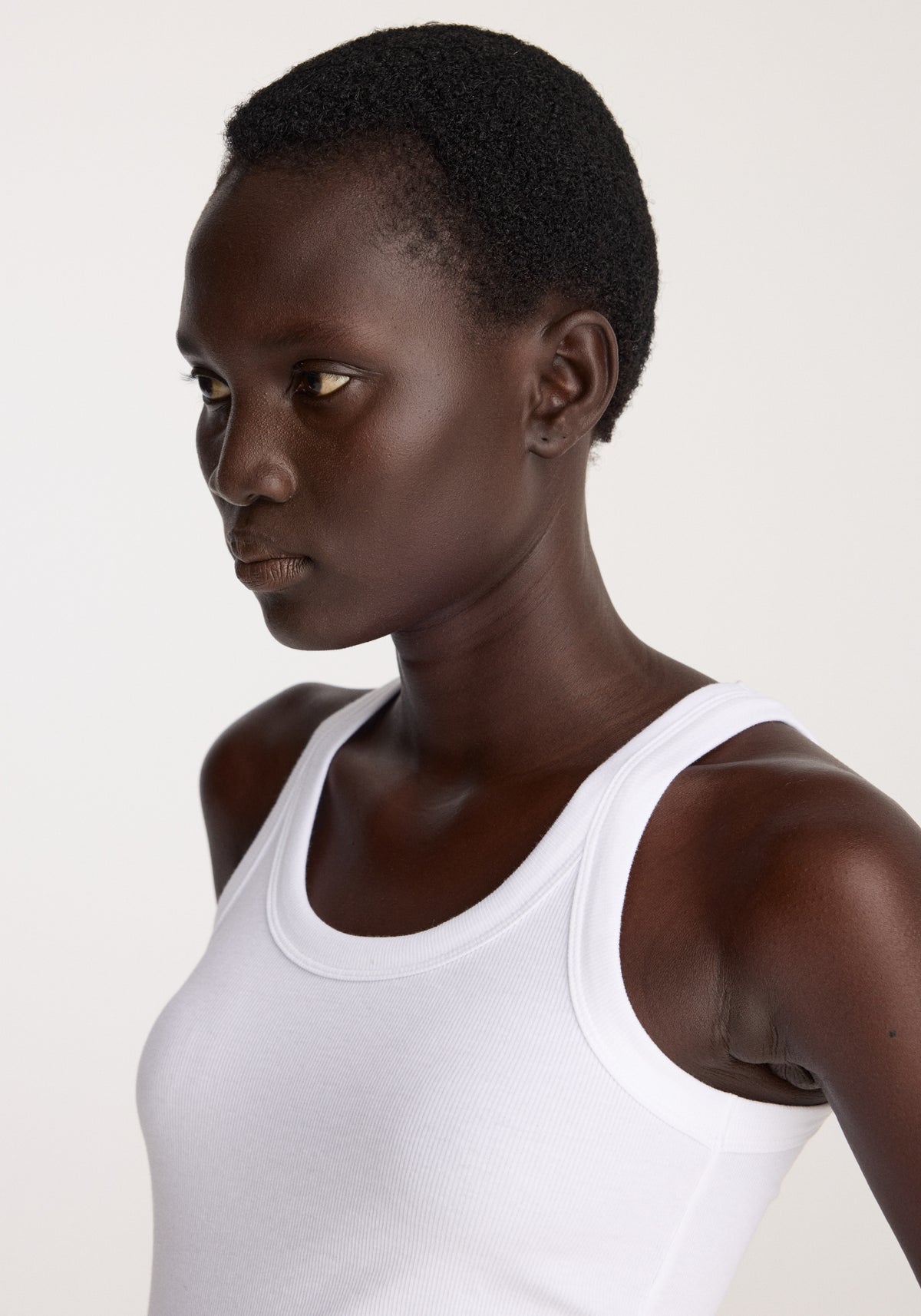 Scoop knitted top | optic white worn by a model, featuring a white scoop neckline and sleeveless design in a close up portrait view