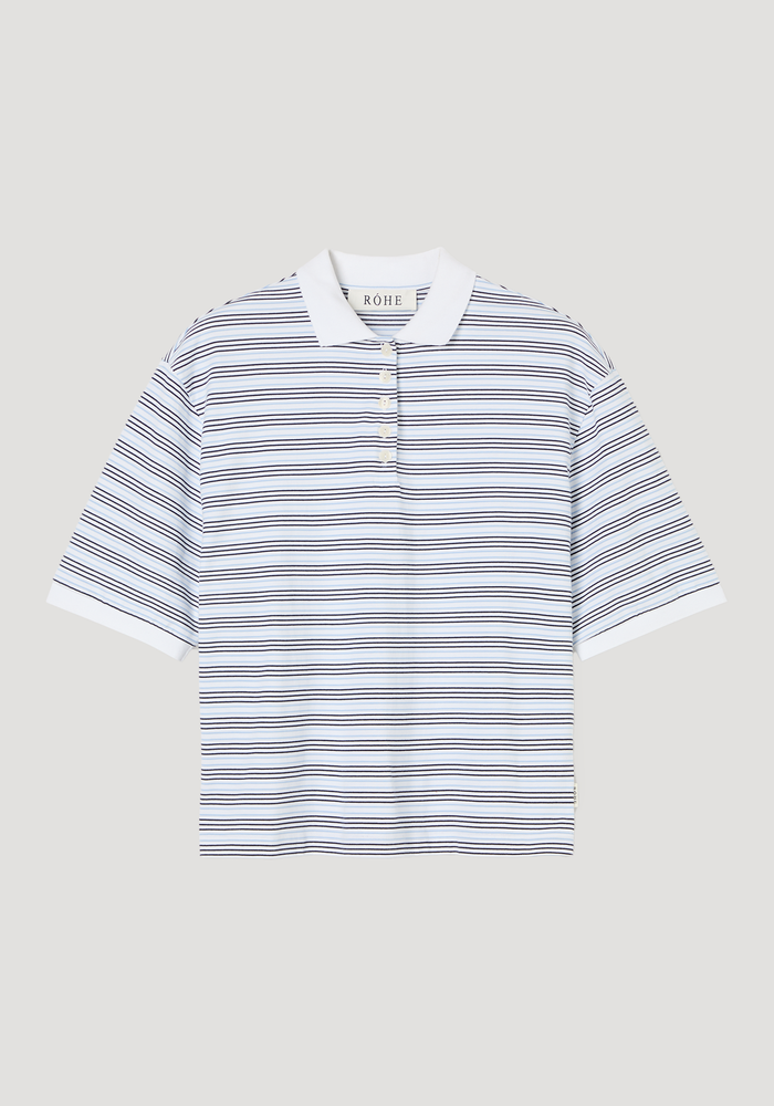 Striped oversized polo with white and light blue stripes, white ribbed collar, and four-button placket. Features an oversized fit, crafted from 100% cotton.