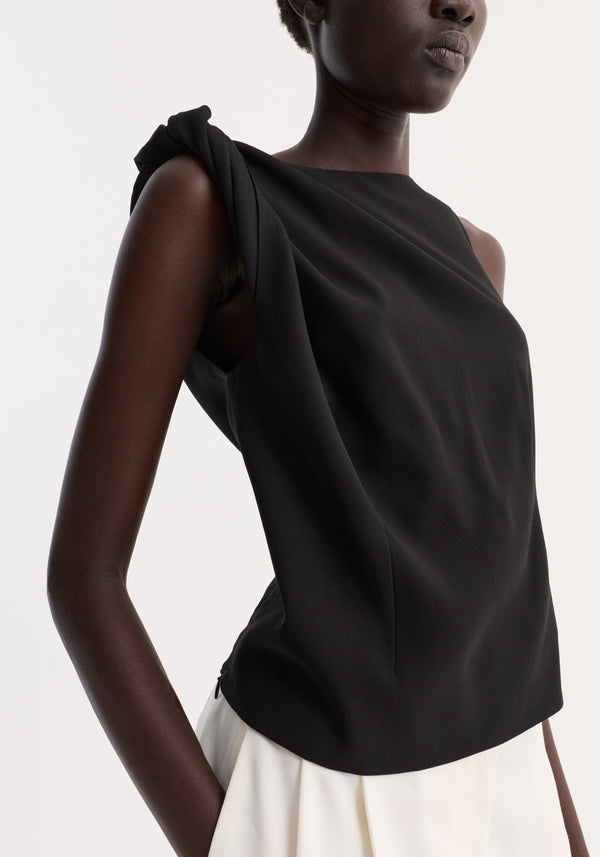 Model wearing Draped linen silk top | black, showcasing a twist detail on one shoulder, boat neck, and gathered waist for an asymmetrical silhouette.