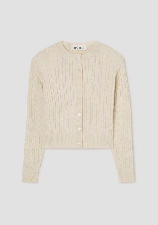 Fine merino cable cardigan in cream, featuring a round neckline, button-front, ribbed cuffs, subtle shoulder pads, and a slightly cropped silhouette.