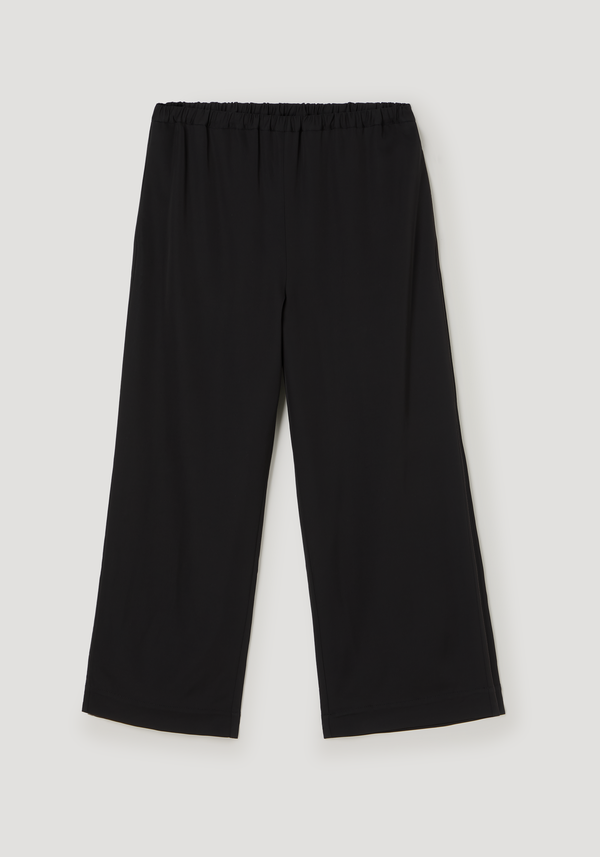 Cropped wide leg trousers in black, featuring an elasticated waist, ankle length, and side pockets, crafted from technical jersey fabric.