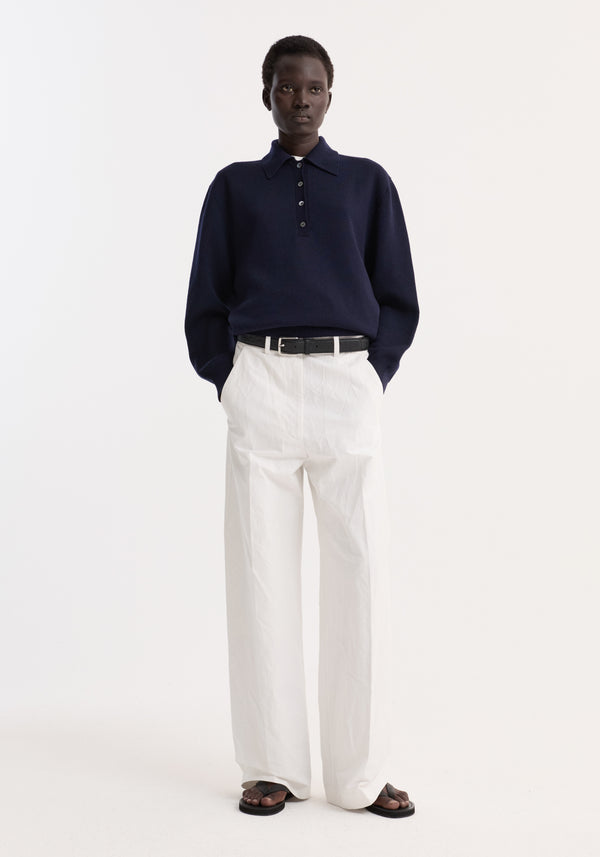 Model wearing Classic loose fit chino in optic white, featuring a baggy relaxed fit with side pockets, tailored waistband, and elongated legs, styled with a navy knit top.