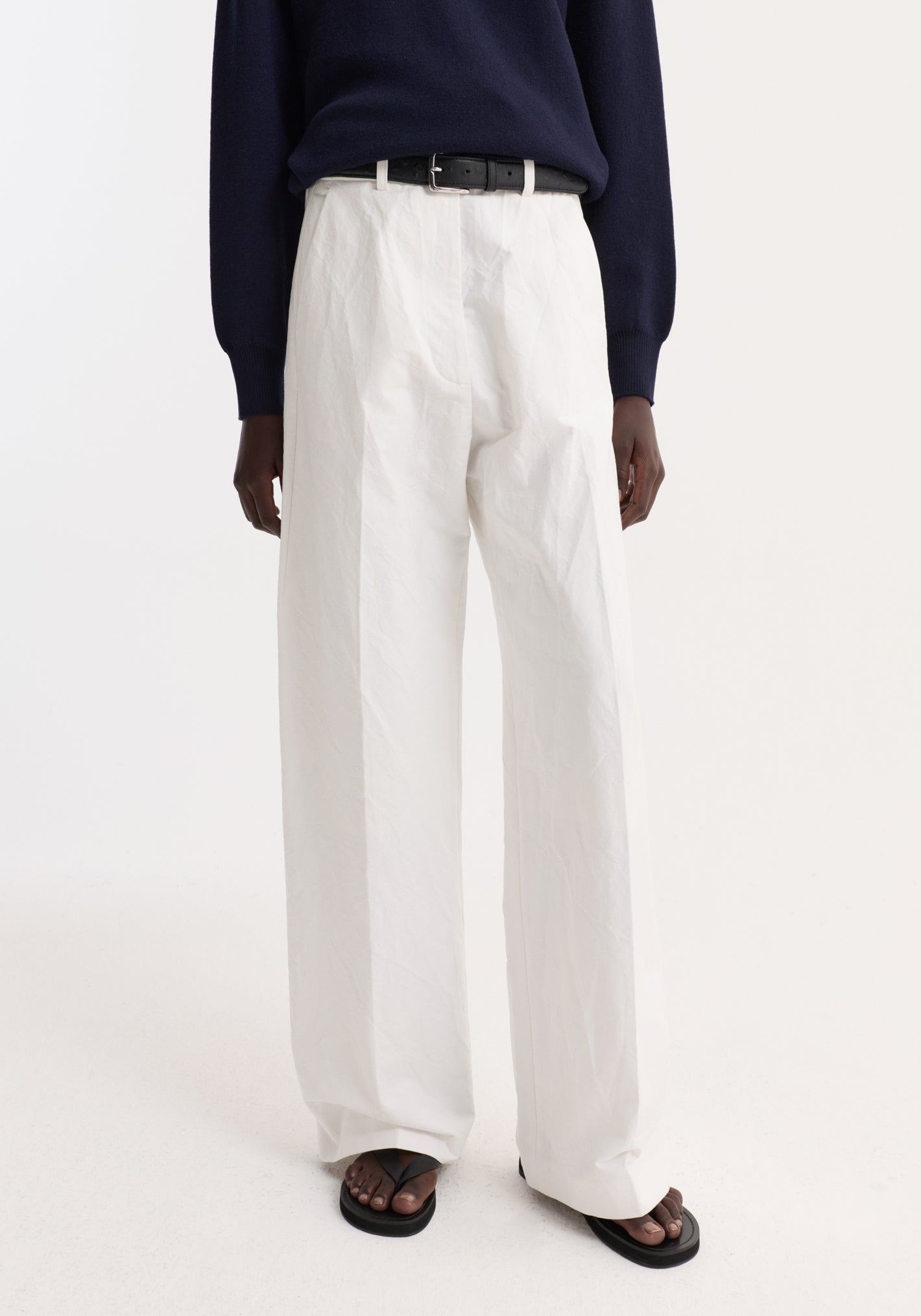 Classic loose fit chino in optic white, featuring a high-waisted, wide-leg design with a tailored waistband and side pockets, worn with a black belt.