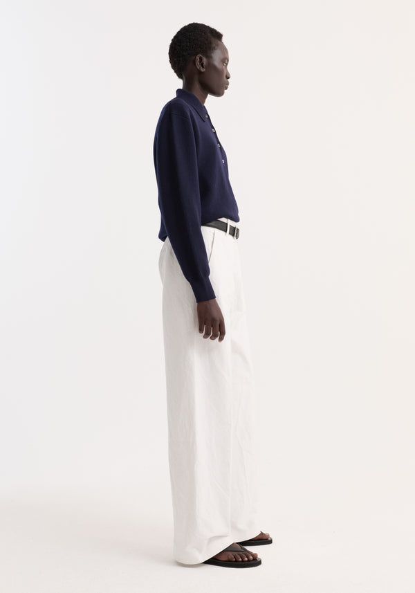 Model wearing Classic loose fit chino in optic white, showcasing a baggy relaxed fit with side pockets, paired with a navy button-up polo shirt.