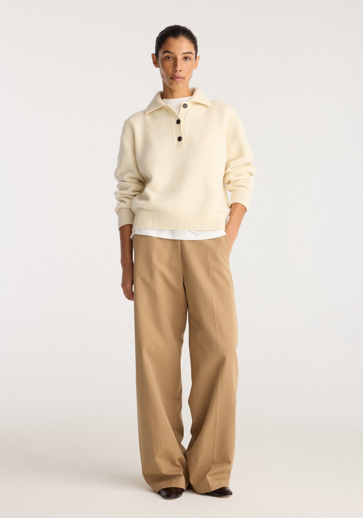 Classic loose fit chino | beige worn by a model with a cream collared sweater in a studio setting styled with black shoes