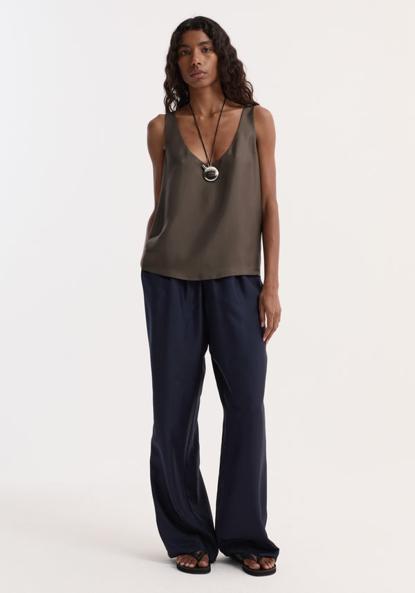 Model wearing Relaxed silk trousers | night, featuring wide legs and an elasticated waistband with a faux fly and two-button detail, paired with a sleeveless top.