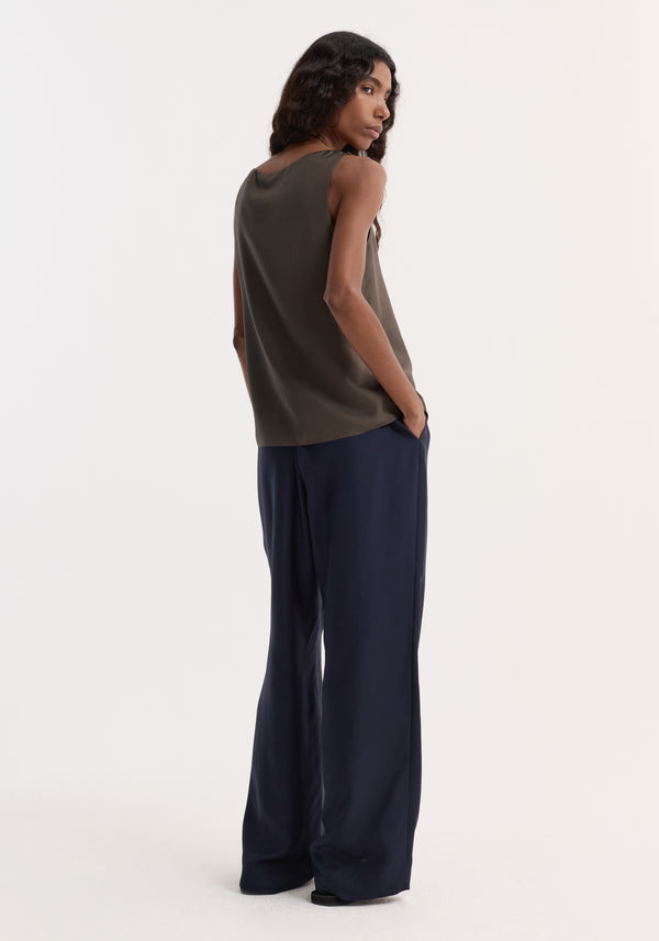 Relaxed silk trousers | night: Model wears wide-leg navy trousers with an elasticated waistband and faux fly, paired with an olive-green top.