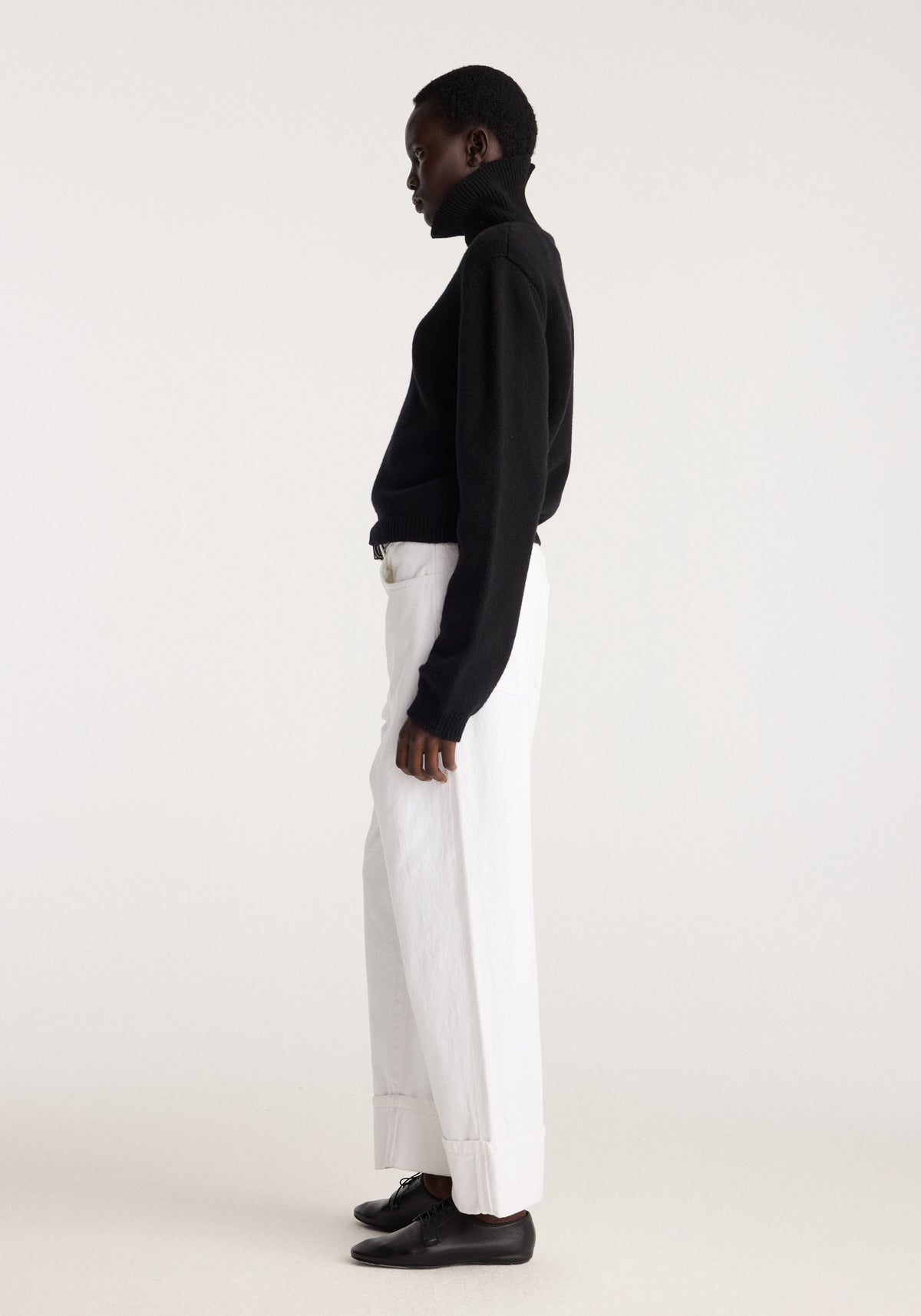 Baggy fit turn-up denim | optic white shown in side profile with a relaxed leg, folded cuffs, and a model wearing black knitwear and loafers