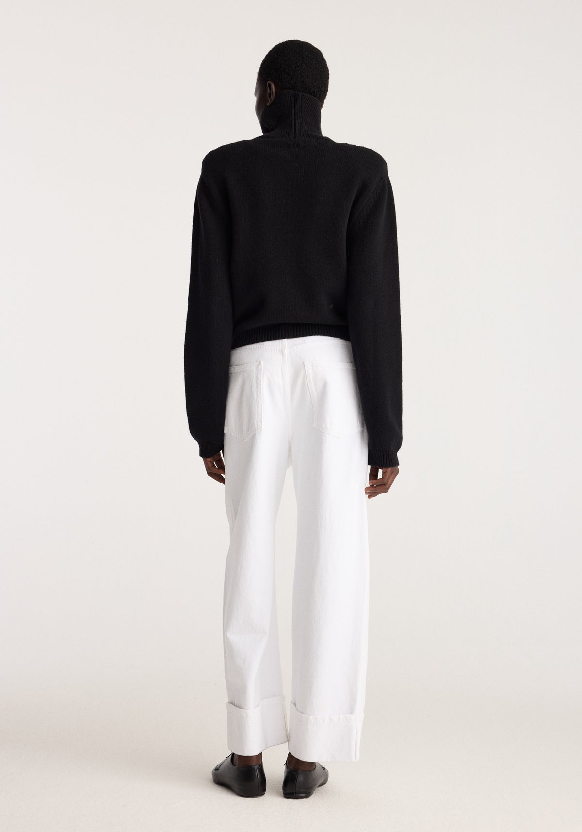 Baggy fit turn-up denim | optic white shown from the back on a model with wide legs and folded hems styled with a black top and black shoes